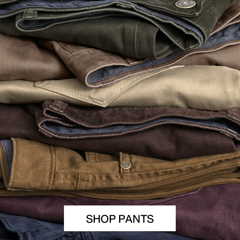 Stack of men's pants in assorted neutral colors and fabrics with text that reads shop pants.
