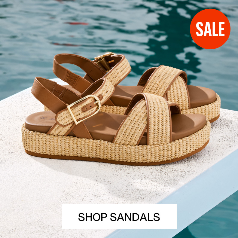 Two pairs of womens cream colored woven loafers sitting in a palm tree.