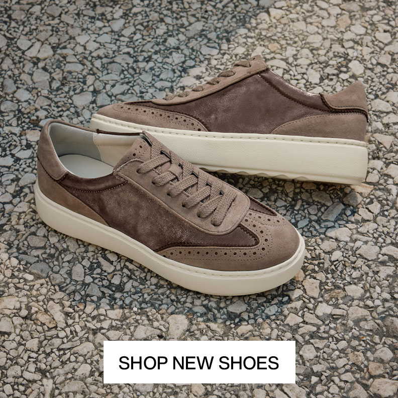 Pair of taupe suede women's sneakers with textured panels and white soles on a stone surface.