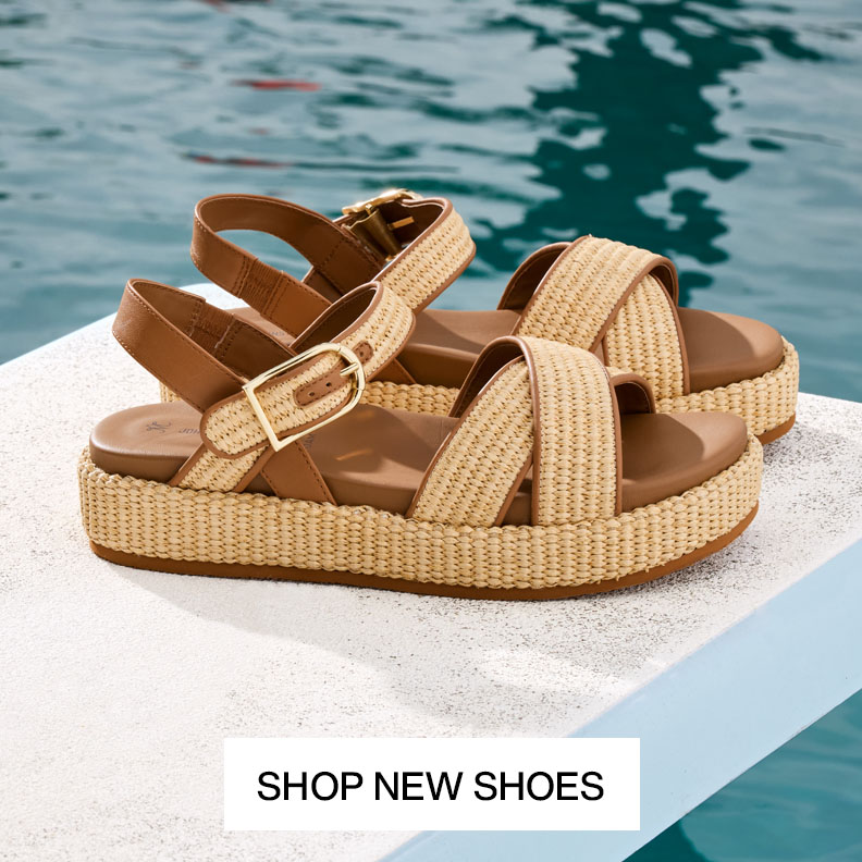 Two pairs of womens cream colored woven loafers sitting in a palm tree.