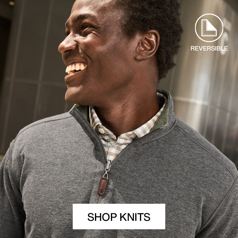 Smiling man wearing a gray quarter-zip knit sweater over a plaid shirt with text that reads shop knits.